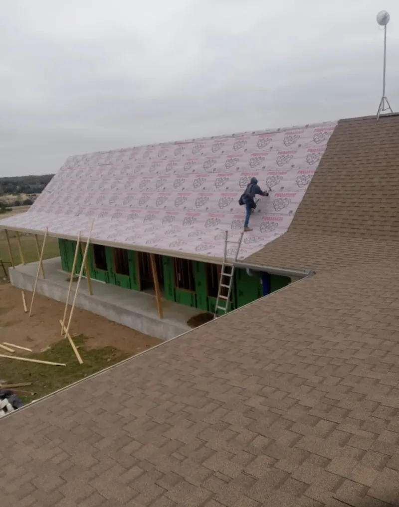 Worker preparing underlayment for a metal roof installation in Bithlo